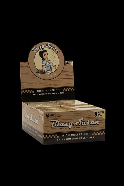 A box of “Blazy Susan” High Roller Kit rolling papers, featuring a vintage-style illustration of a woman and text indicating 8-meter rolls and included tips.