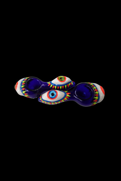 Hand-blown glass pipe shaped like two eyes with colorful detailing, isolated on a black background.