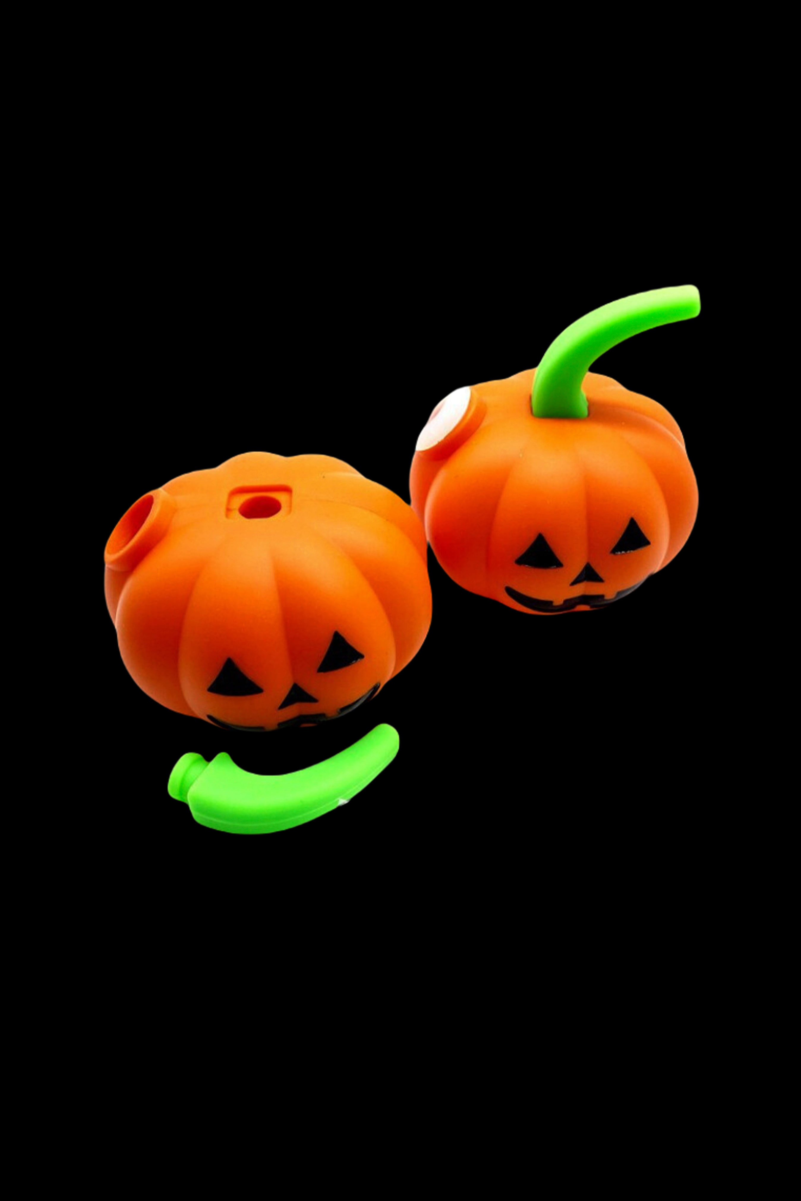 Two orange jack-o'-lantern-shaped cannabis pipes with green stems float against a black background.