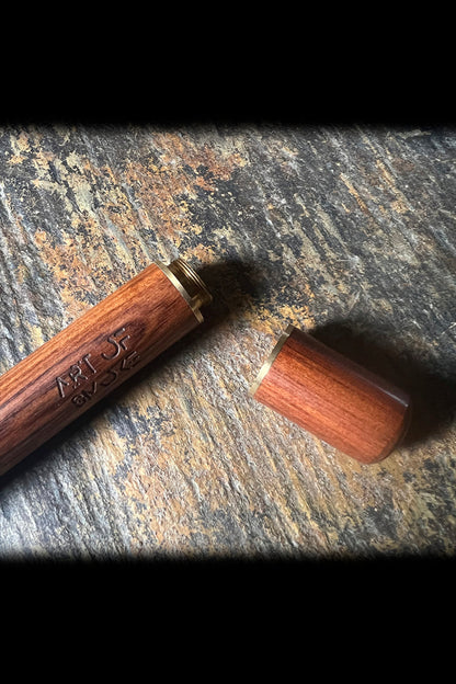 Wooden cannabis pipe with screw-on cap, resting on a textured surface.