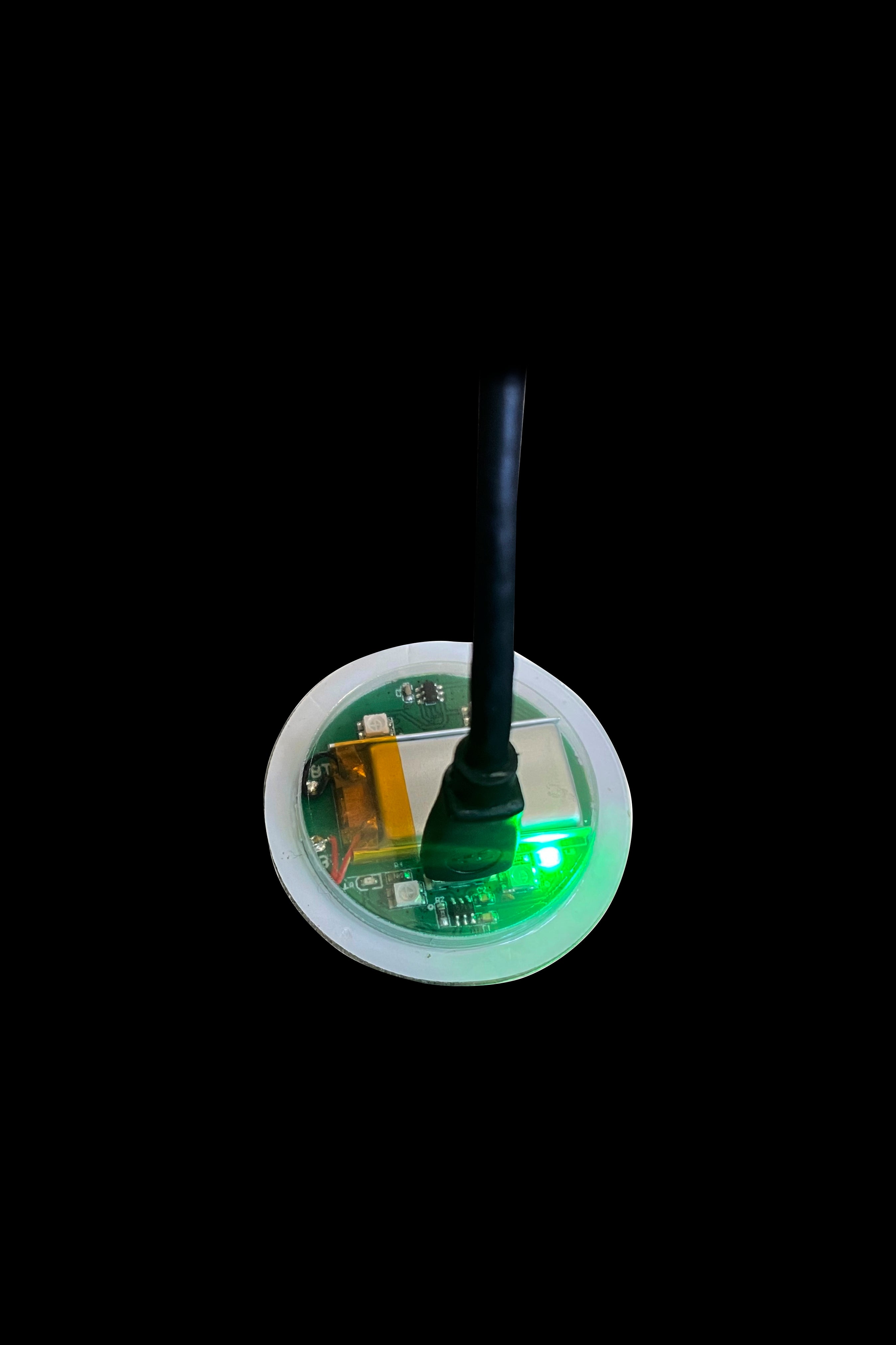 Close-up of a cannabis oil vape cartridge’s internal components illuminated with a green light, against a black background.
