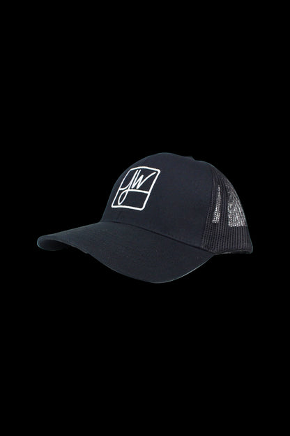 Angled close-up of a black Jane West Snapback Hat with white embroidered "JW" logo and mesh back against a black background