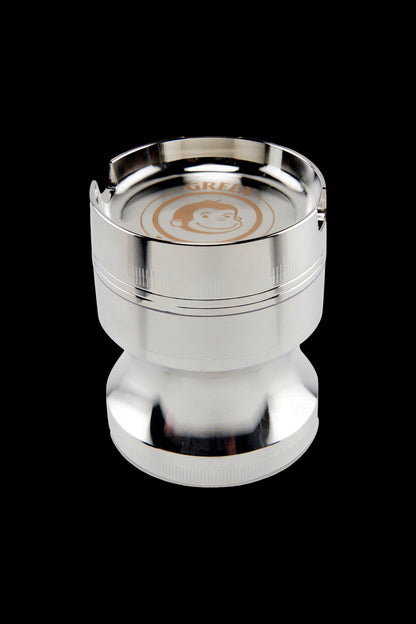Top-down view of the metallic Green Monkey Chacma Grinder with Ashtray showing its shiny silver rim, engraved monkey logo and three notches.