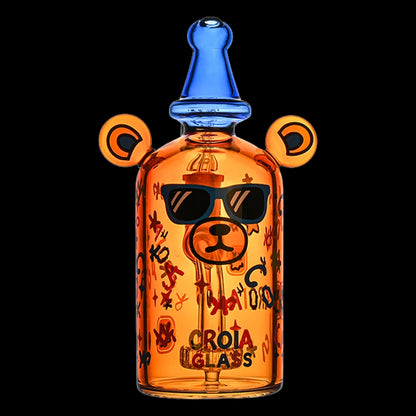 Centered front view of the Croia Glass Cool Teddy Bear Dab Rig with Showerhead Perc | Croia Glass, an orange bear-shaped glass piece with blue top and sunglass decal against black