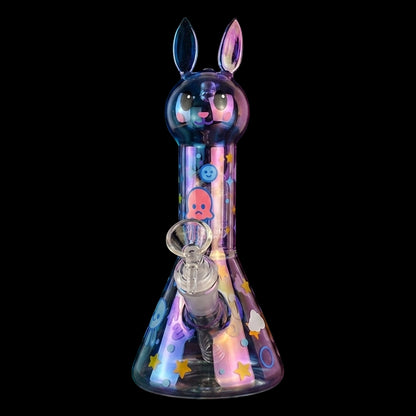 Centered front view of the Croia Glass Cute Bunny Beaker Bong with Tree Perc showing a iridescent bunny head mouthpiece, colorful stickers, and clear bowl against black