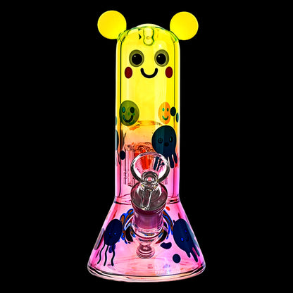 Center-front view of the Croia Glass Cute Character Beaker Bong with Jellyfish Design showing a yellow-topped smiling face and colorful jellyfish decals on a pink flared base