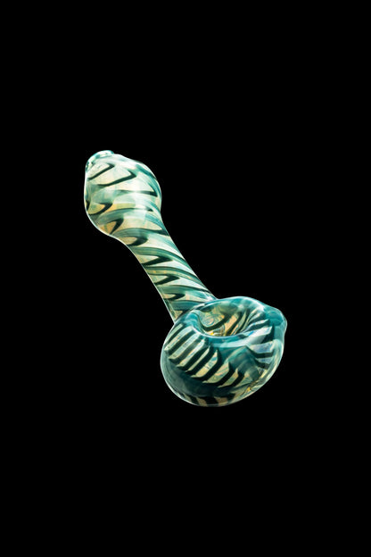 Green and white swirled glass pipe against a black background.