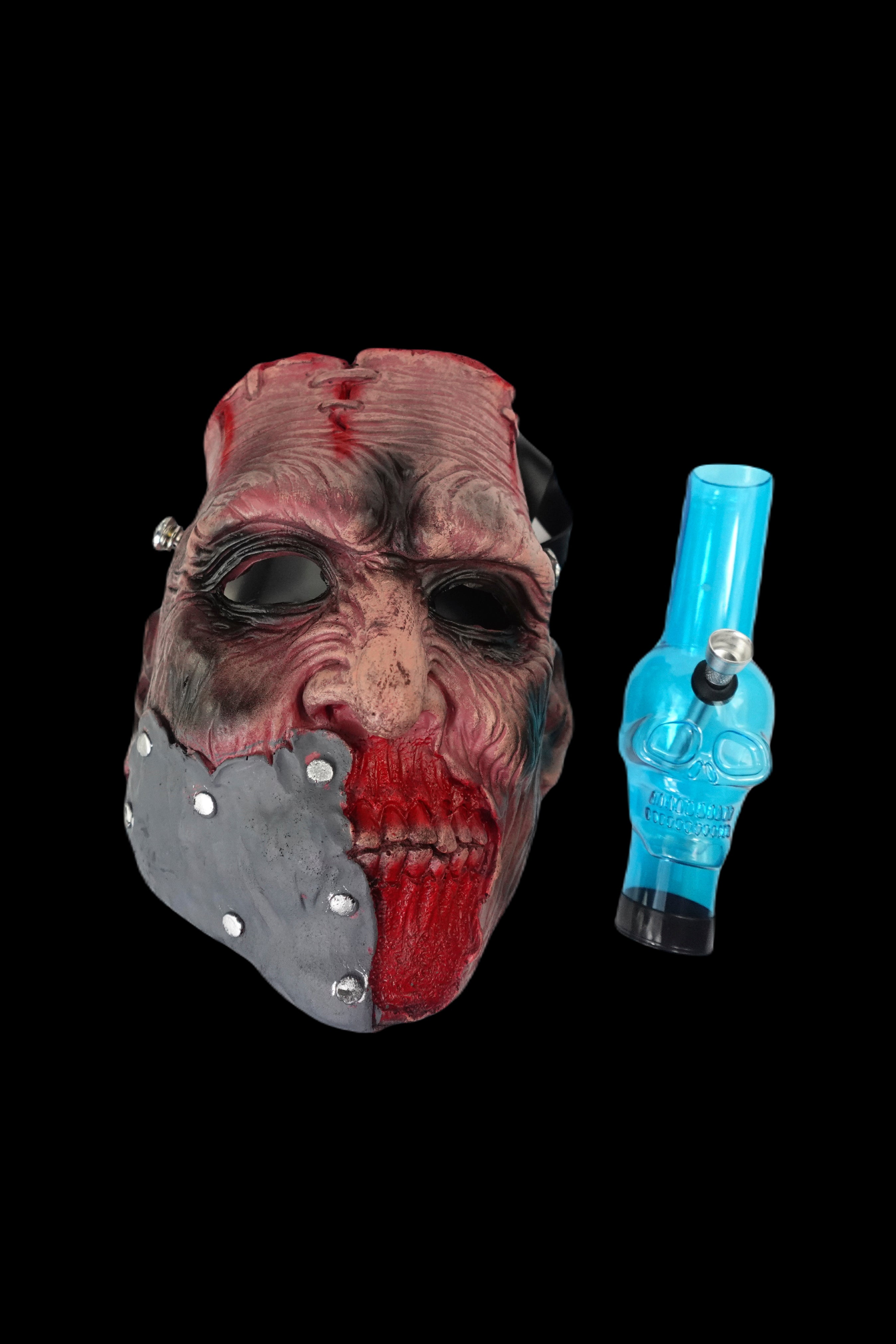 Horror-themed cannabis accessory display featuring a realistic zombie mask and a blue glass pipe against a black background.