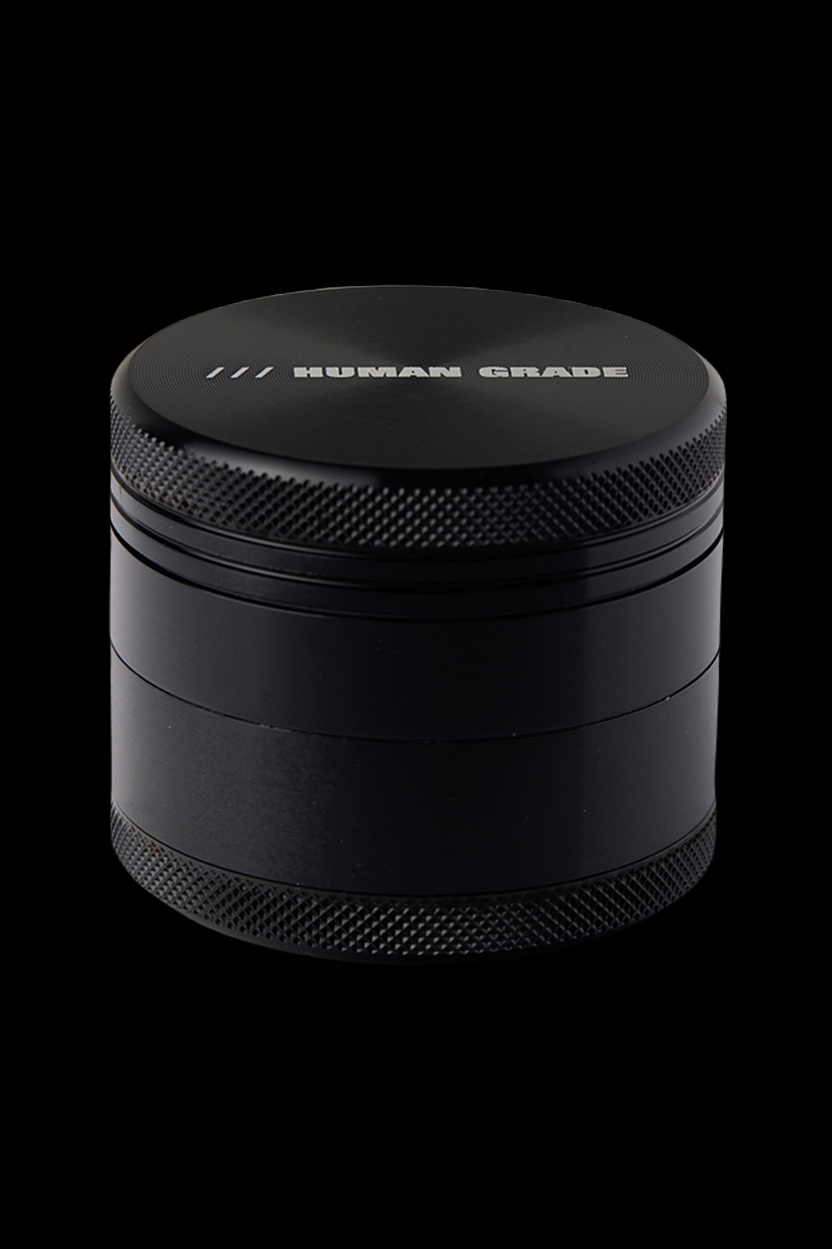 Black four-piece cannabis grinder with "HUMAN GRADE" etched on top.