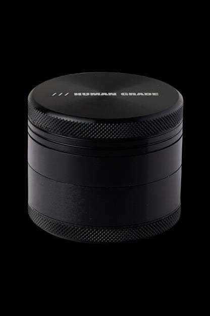 Black four-piece cannabis grinder with "HUMAN GRADE" etched on top.