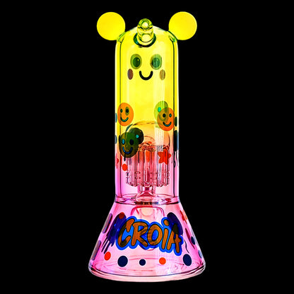 Centered, front view of the Croia Glass Cute Character Beaker Bong with Jellyfish Design showcasing a yellow top with round "ears" and smiling faces over a pink beaker base.