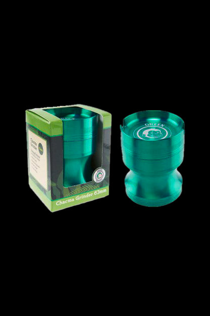 Close-up front view of the Green Monkey Chacma Grinder with Ashtray in metallic purple shown beside its green-trimmed box on a black background