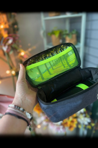 A hand holds open a smell-proof cannabis accessories case revealing bright green buds inside. <start_of_image>