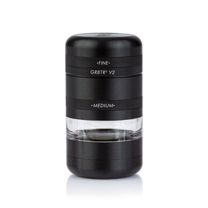 Centered front view of the matte black RYOT GR8TR Jar Body Grinder showing stacked cylindrical sections with textured bands and a clear middle chamber.