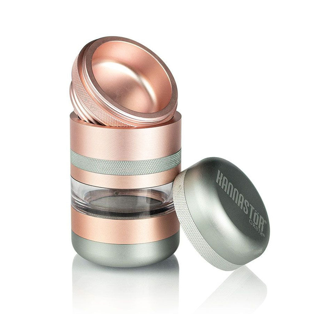 Angled close-up of the rose-gold and silver RYOT GR8TR Jar Body Grinder with its lid removed and placed beside the clear middle chamber.