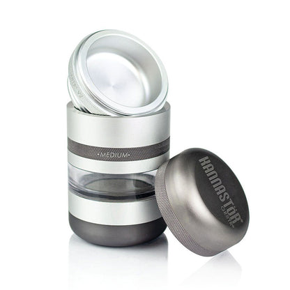 Three-quarter view of the silver RYOT GR8TR Jar Body Grinder with its lid removed and placed beside the clear midsection reflecting studio light.