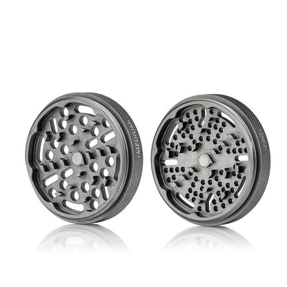Two angled halves of the RYOT GR8TR Jar Body Grinder shown on a white background, revealing textured rims and staggered perforated grinding plates.