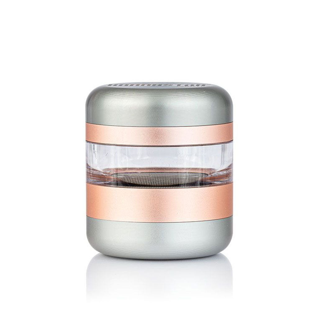 Centered front view of the RYOT GR8TR Jar Body Grinder showing its metallic silver and rose-gold bands with a clear middle chamber on a white background