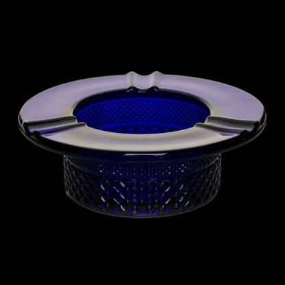 Blue glass ashtray with three indentations, isolated on a black background.