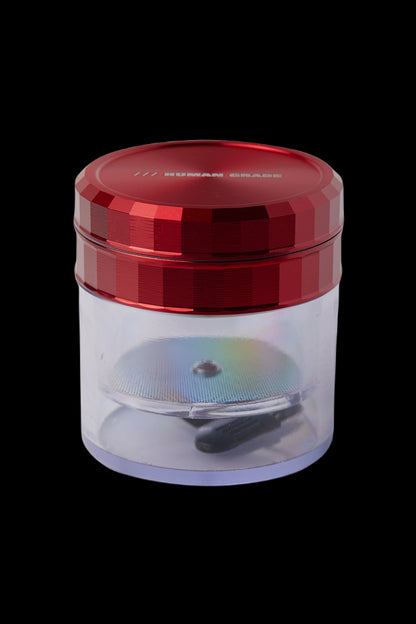 Red and clear cannabis grinder with visible ground material inside.