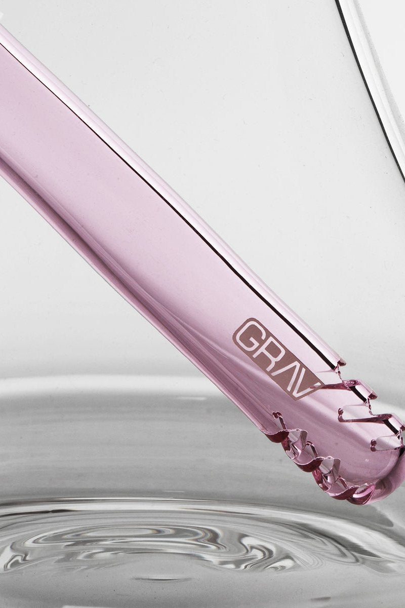 A lavender glass water pipe with the "GRAV" logo dips into rippling water.