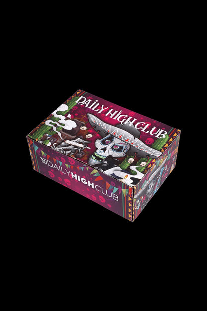 A colorful, patterned box for “Daily High Club” cannabis accessories, featuring a skull graphic and ornate designs.