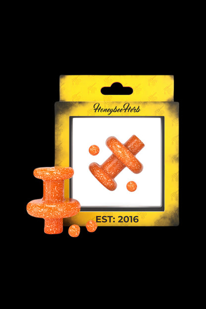 Packaged cannabis edibles, orange cross-shaped gummies with “HoneybeeHerbs” branding and “EST: 2016” text.