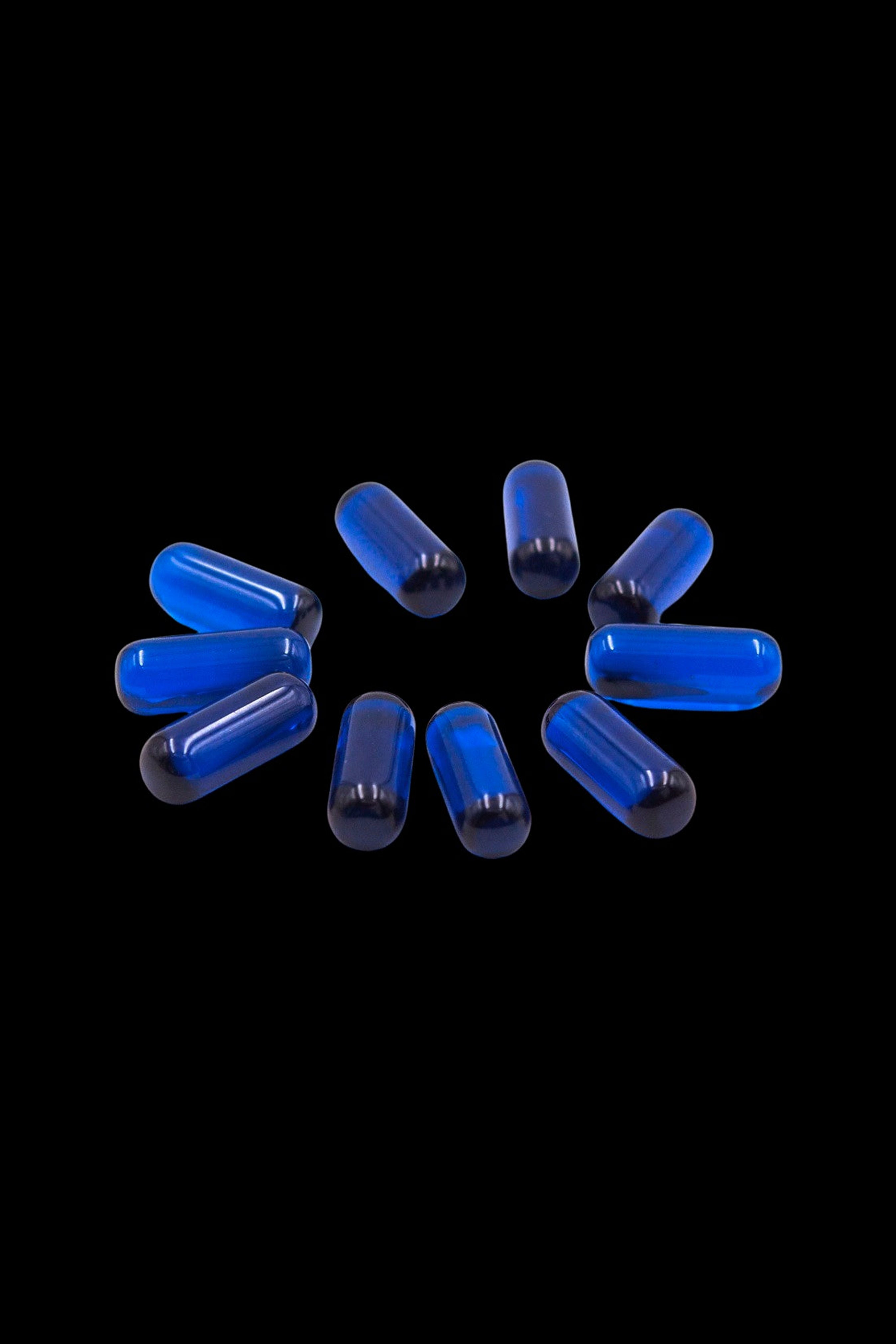 Blue cannabis capsules scattered on a black background.