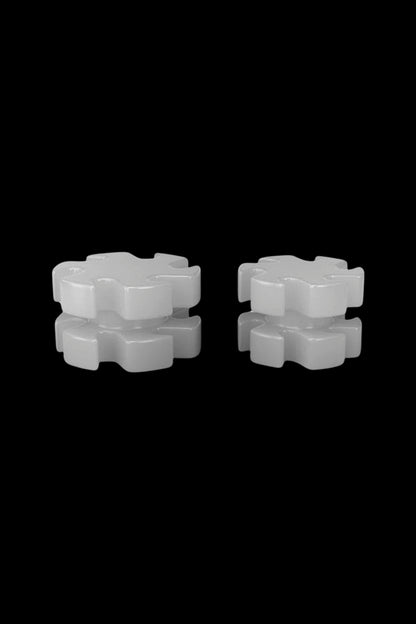 Two white, stackable cannabis filter tips against a black background."