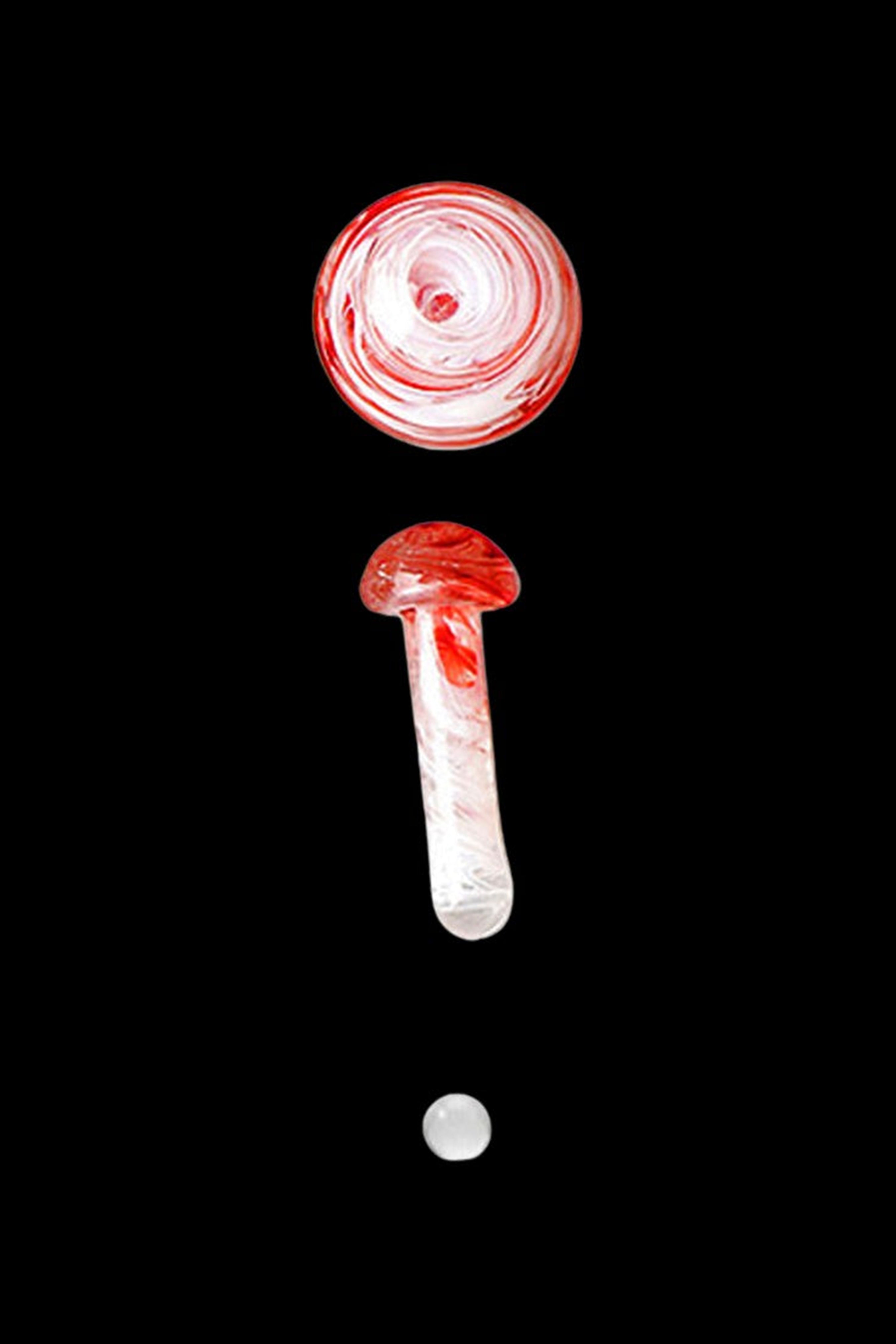Red and white swirled glass cannabis oil burner pipe and carb cap against a black background.