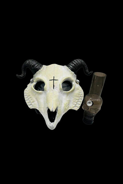 Goat skull with a glass oil rig inside its mouth, featuring a cross on its forehead, against a black background.