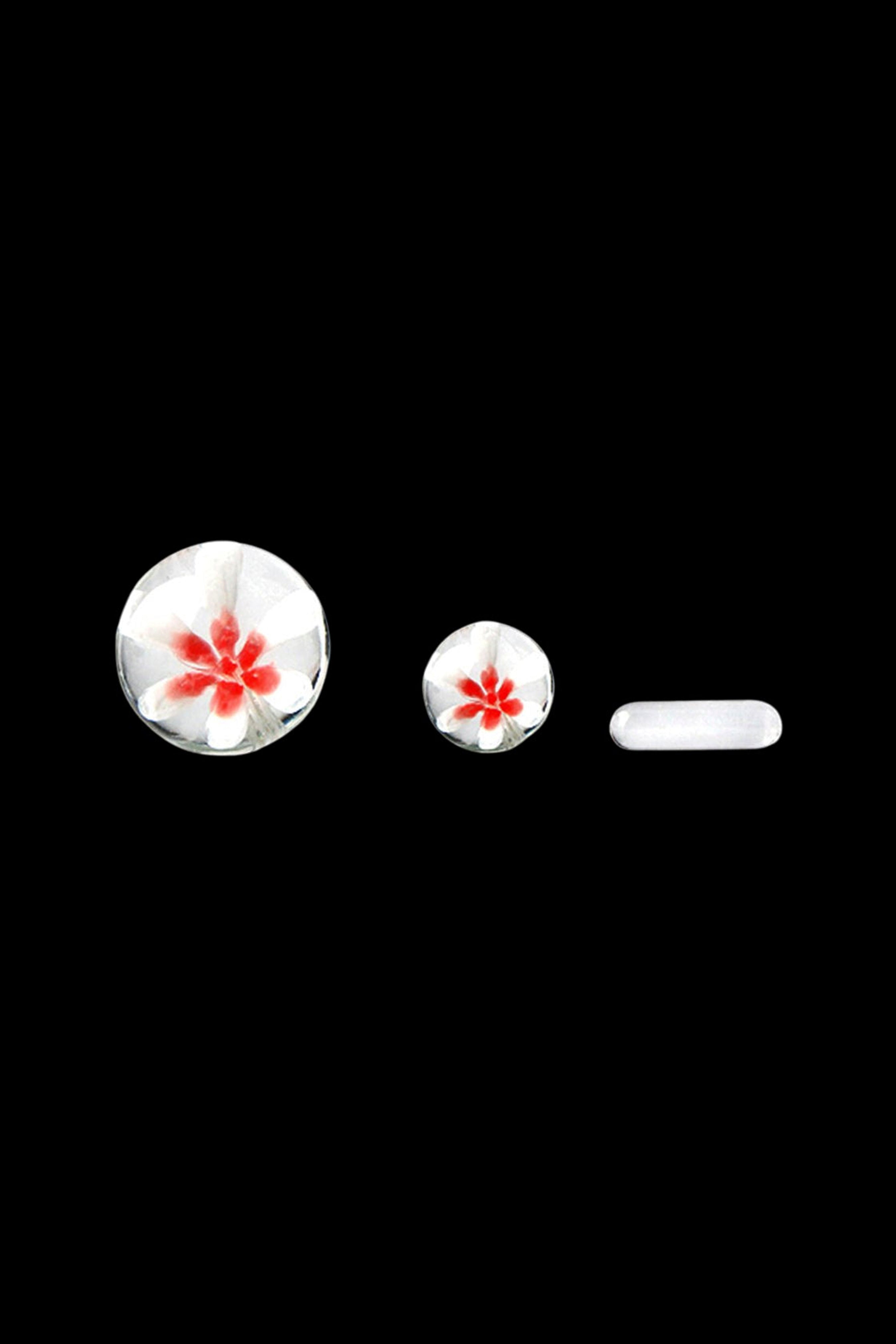Glass cannabis pipe components with red floral designs on a black background.