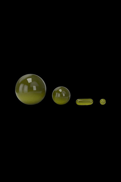 Green glass cannabis oil capsules in varying sizes against a black background.