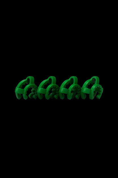 Low-angle close-up of four green Honeybee Herb Keck Clip pieces lined up across the bottom against a black background.