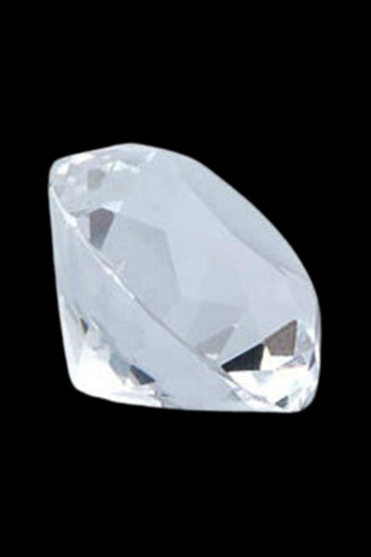 Close-up angled view of a faceted clear gem-shaped piece from The Stash Shack Diamond Cut Glass Carb Cap against a black background.