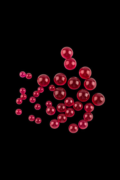 Close-up of clustered glossy red spheres against a black background showing The Stash Shack Ruby Terp Pearls.