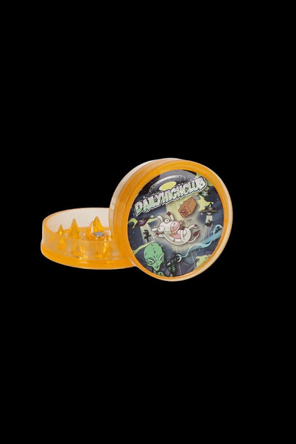 Orange grinder with alien-themed artwork, open to reveal ground cannabis.