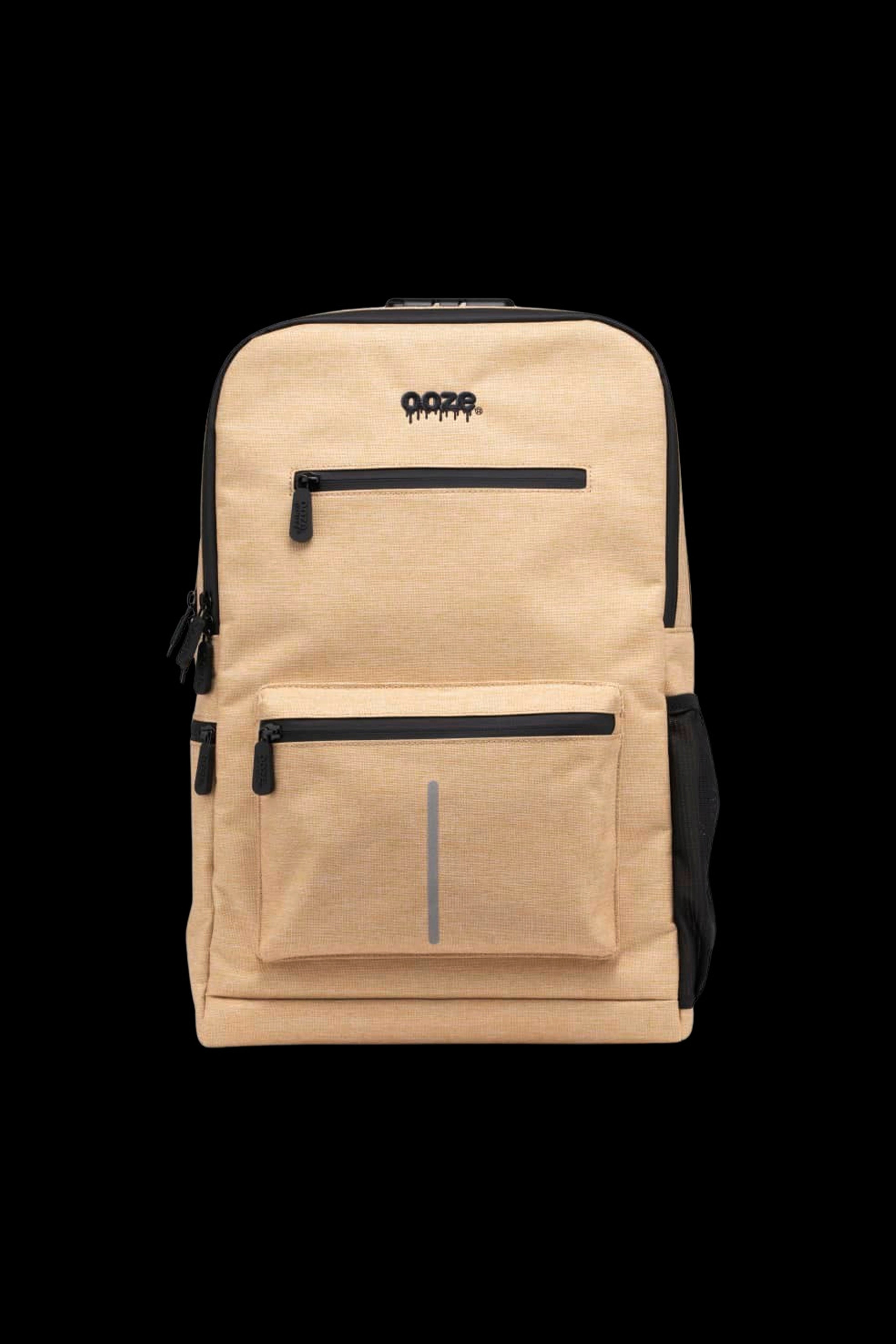 Centered front view of the tan Ooze Traveler Smell Proof Backpack showing two zippered front pockets, black trim, and embossed logo.