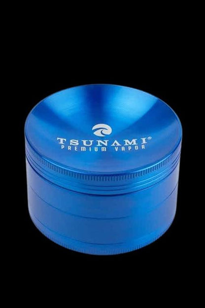 Blue metal cannabis grinder with “Tsunami Premium Vapor” branding.