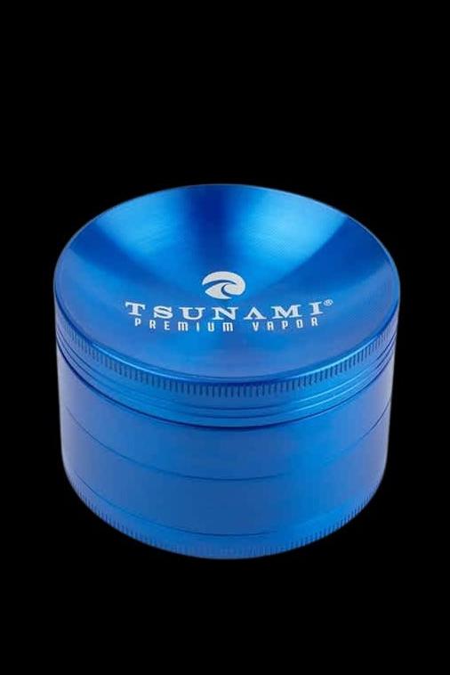 Blue metal cannabis grinder with “Tsunami Premium Vapor” branding.