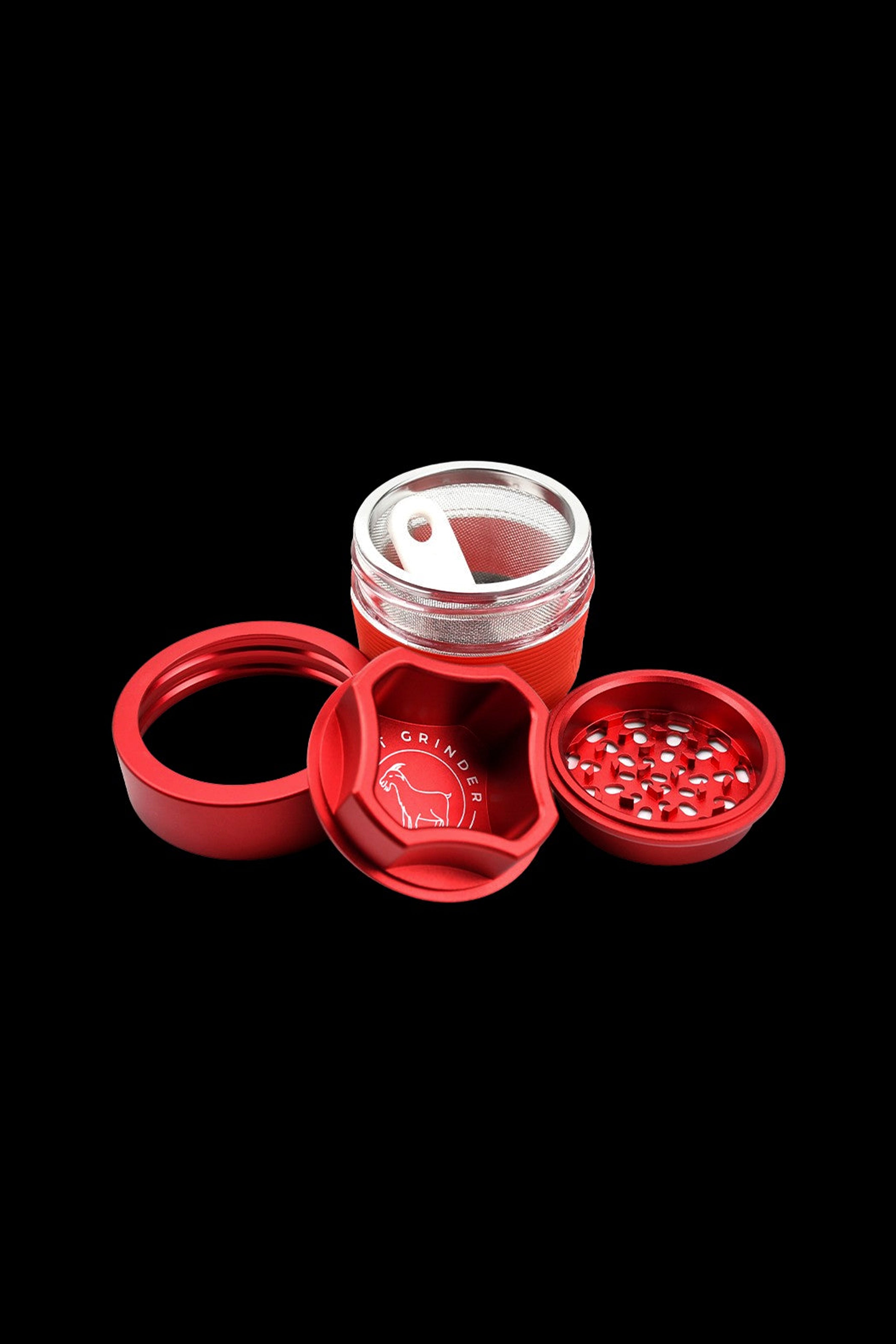 Red and silver cannabis grinder disassembled on a black background.
