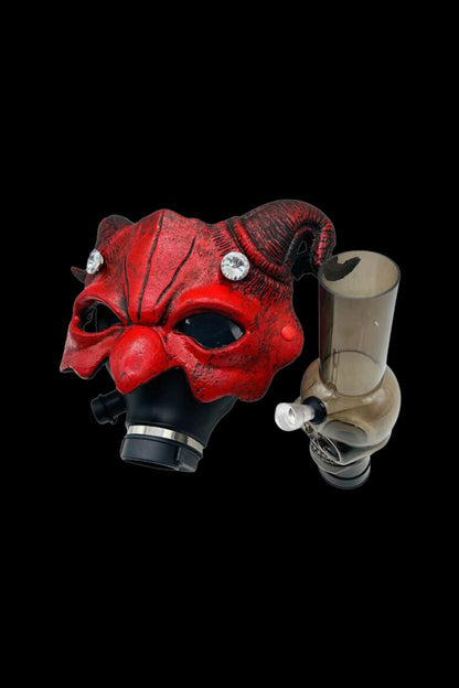 Red, ornate mask with a glass pipe beside it, isolated on a black background.