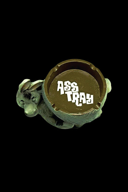 A ceramic ashtray shaped like a coiled snake with “ASS TRAY” written on its surface, set against a black background.