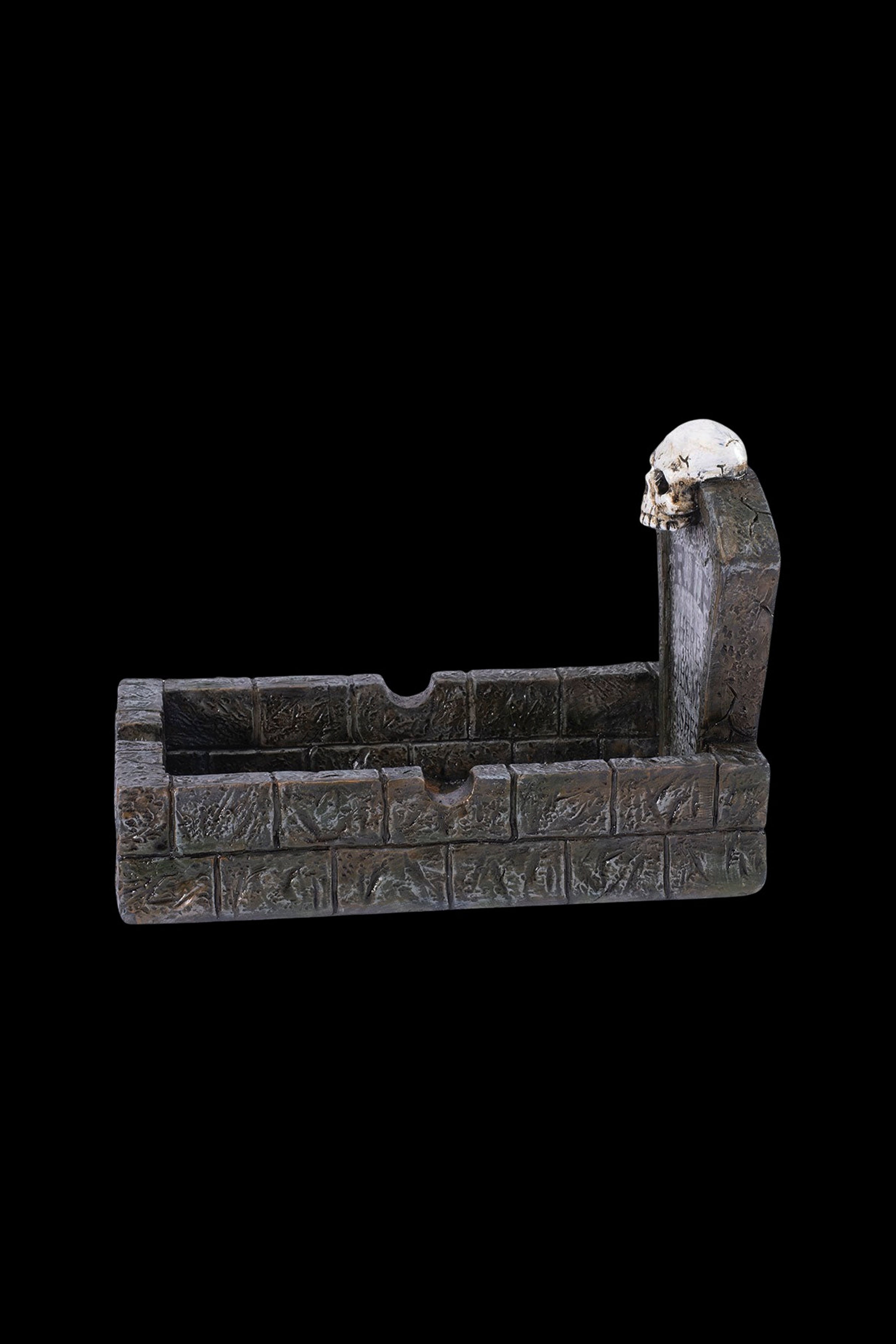 A gothic-style ashtray shaped like a stone castle wall with a skull-topped tower, designed for cannabis use.