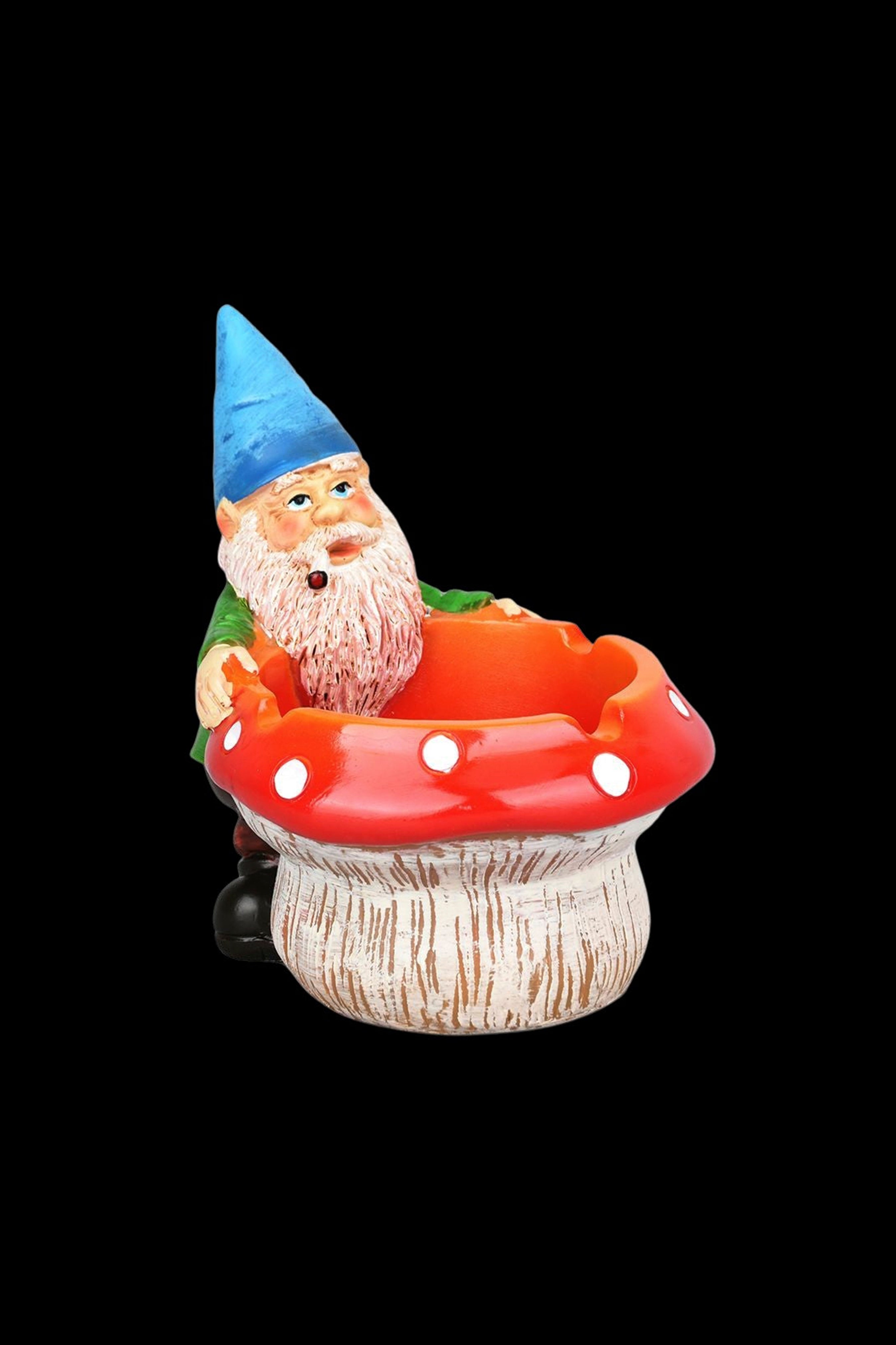 A whimsical garden gnome figurine seated inside a red mushroom-shaped ashtray, likely for cannabis use."
