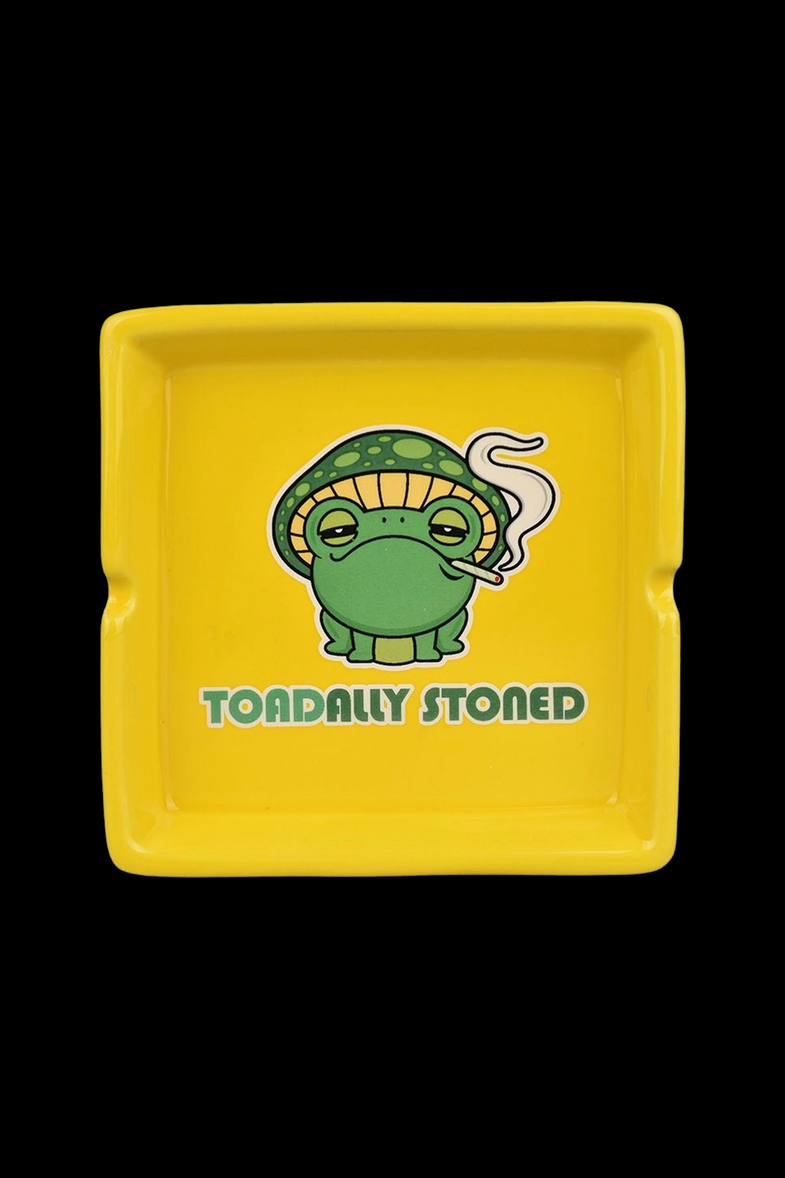 Yellow ashtray featuring a cartoon frog wearing a mushroom cap and exhaling smoke, with the text "TOADALLY STONED."