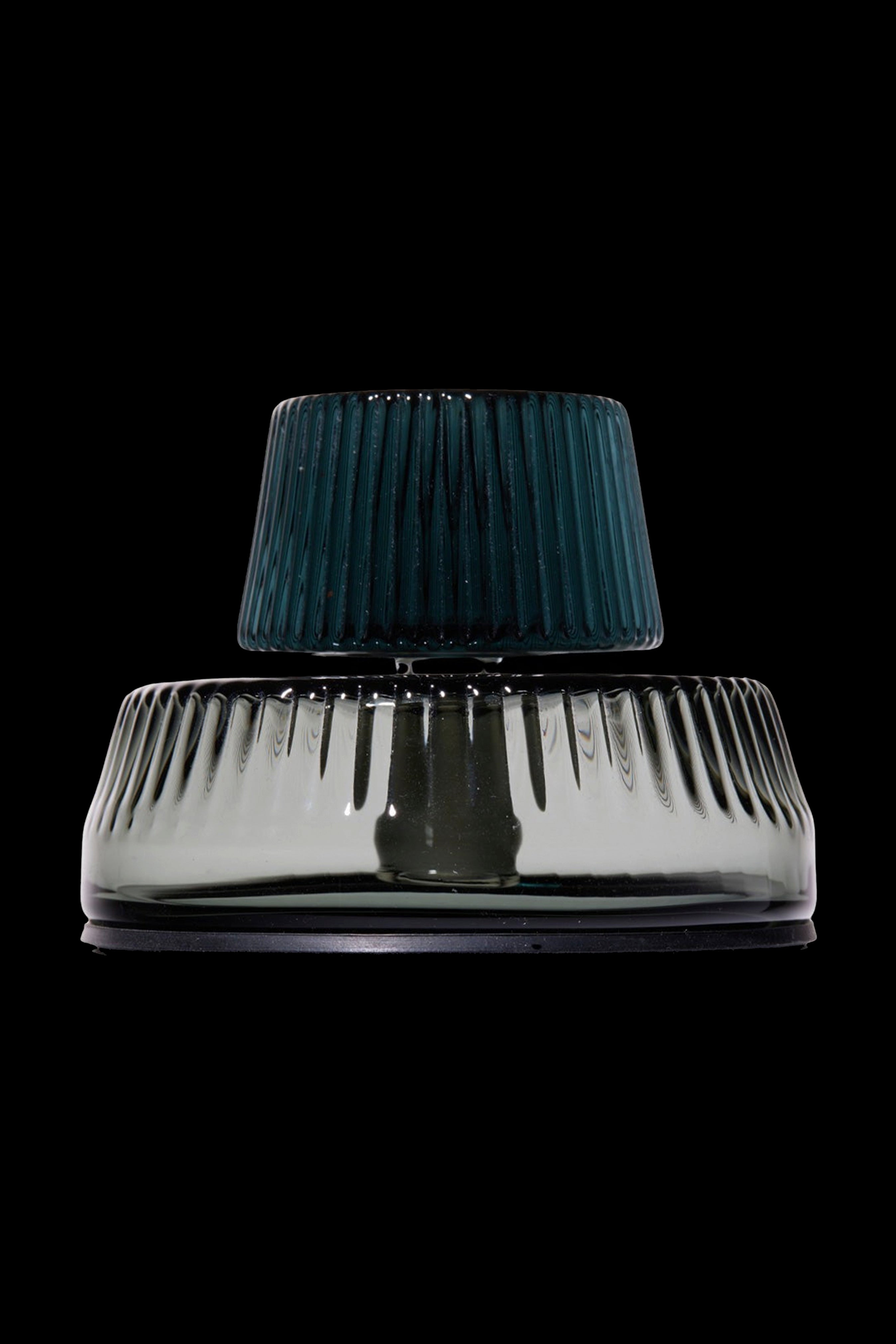 Green and clear glass water pipe against a black background.