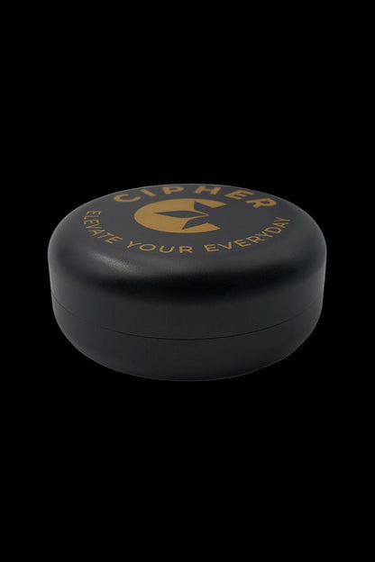 Black, cylindrical cannabis storage container with gold lettering that reads “CIPHER - Elevate Your Everyday.”