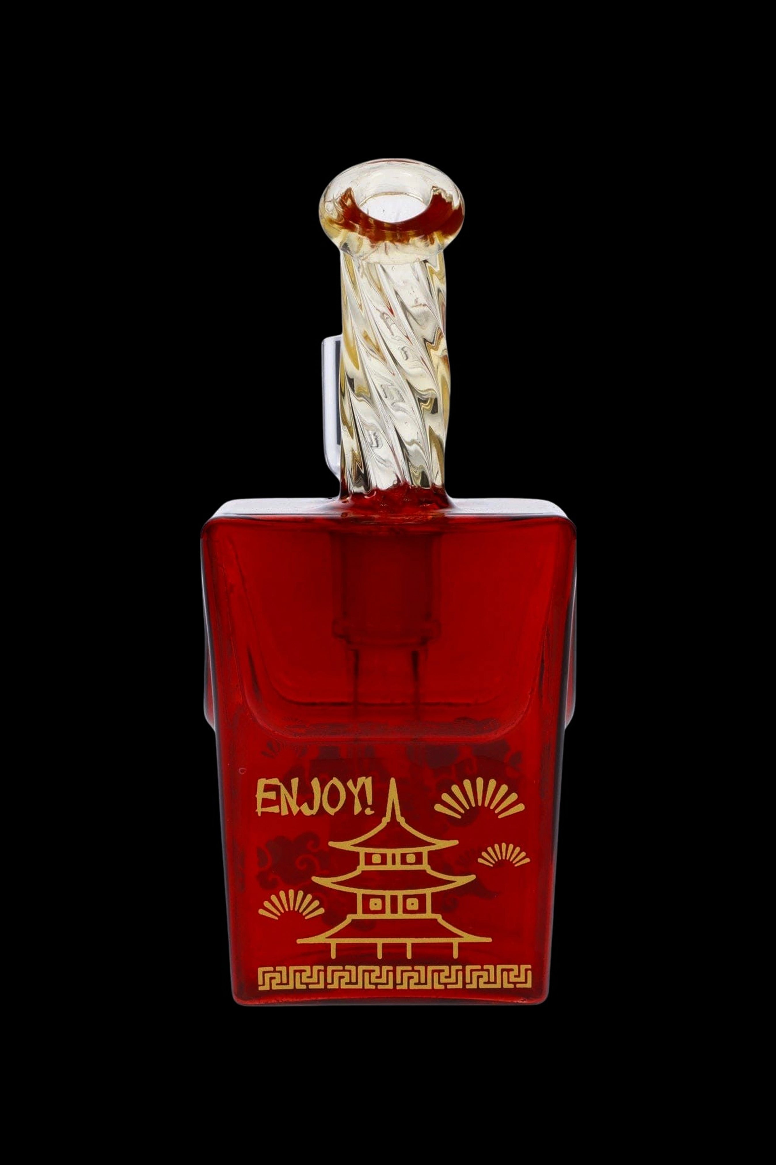 Red glass cannabis oil vial with ornate golden accents and a stylized pagoda design.