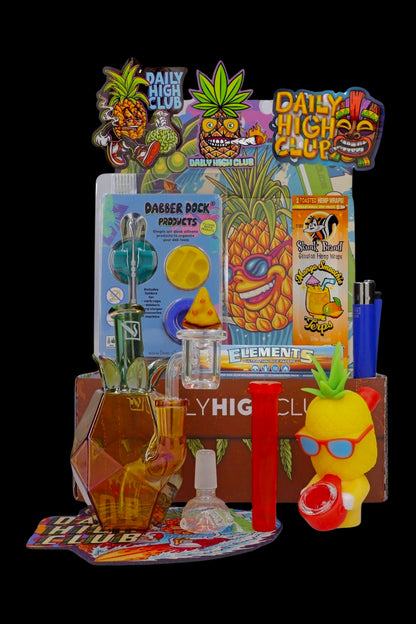 A collection of colorful cannabis accessories including a water pipe, dab rig, hemp wraps, and rolling papers, displayed on a purple mat.